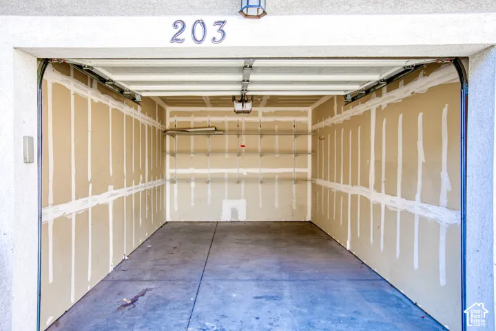 Spacious single-car garage with concrete flooring, automatic garage door opener, and integrated wall shelving