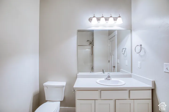 Vanity with integrated sink, four-light fixture, framed mirror, and white cabinetry