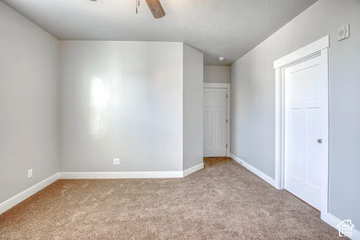 Carpeted flooring, white trim, light gray walls, white paneled doors, and a ceiling fan