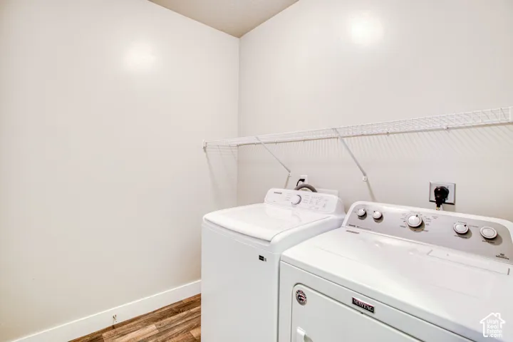 Wood-finish flooring with white baseboards, wire shelving, and white walls