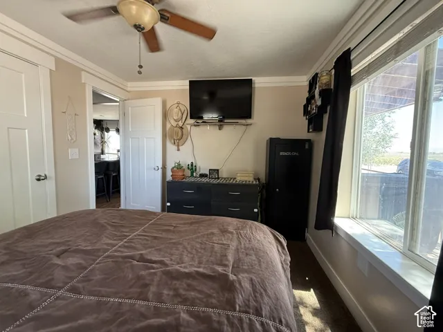 Recessed lighting, wood-finish flooring, ceiling fan, crown molding, and a large window