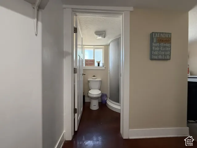 Bathroom featuring a toilet, curved shower enclosure, and a window
