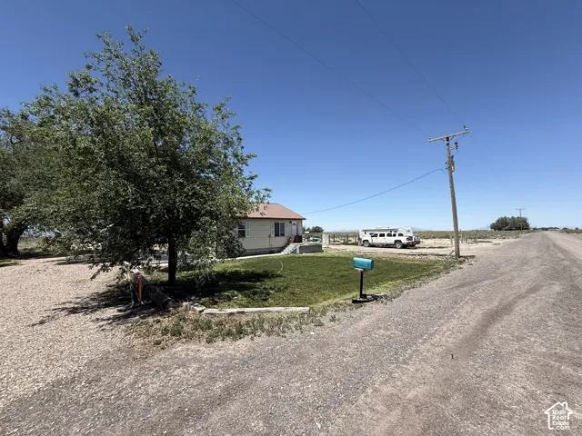 Gravel driveway, mature tree, and a grassy front yard