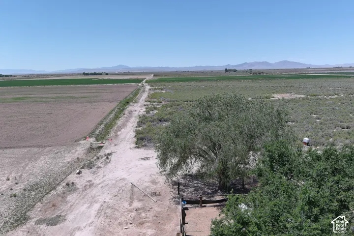 Expansive agricultural land featuring cultivated fields, natural shrubland, and distant mountains under a clear sky