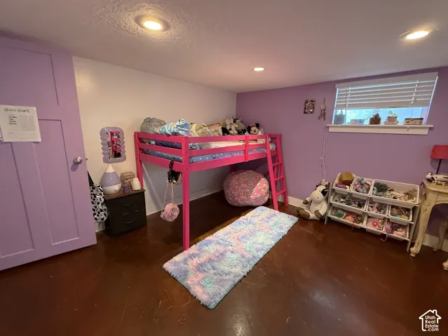 Recessed lighting illuminates the room, featuring a window with horizontal blinds and wood-finish flooring