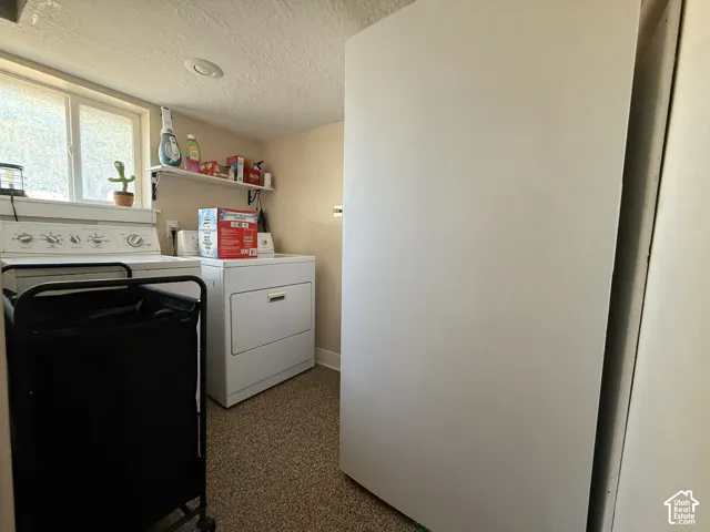 Laundry area with white appliances, built-in shelving, windows, and overhead lighting