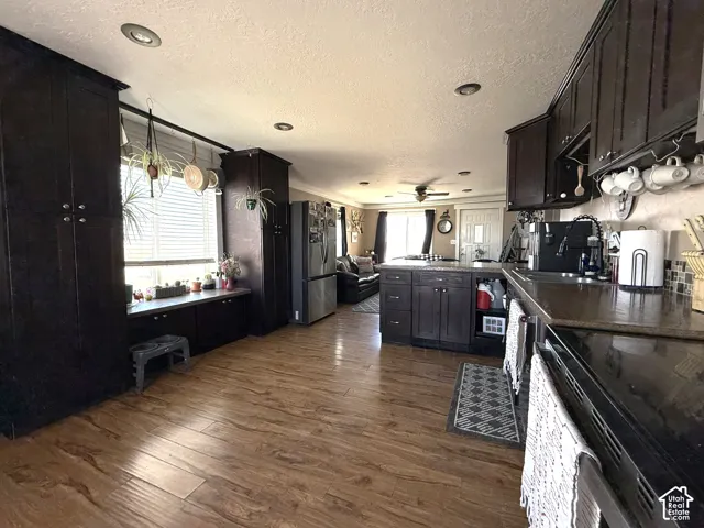 Integrated kitchen featuring dark wood-finish cabinetry, wood-finish flooring, recessed lighting, and a kitchen island with seating