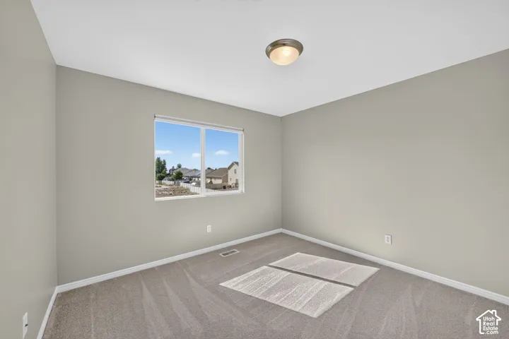 Recessed window with white trim, neutral-toned walls, and grey carpet flooring