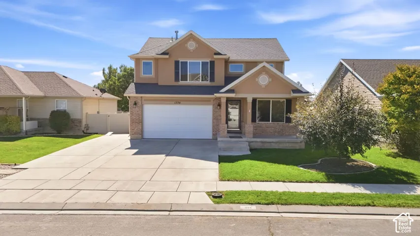 Two-story residence featuring stucco and brick exterior, an attached two-car garage, and a concrete driveway