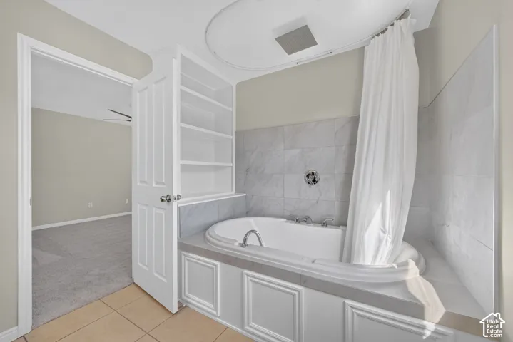 Built-in garden tub featuring panel detailing, recessed built-in shelving, and tile flooring
