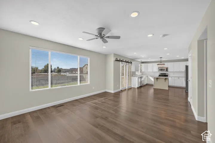 Open-concept living area showcasing wood-finish flooring throughout, recessed lighting, and a ceiling fan