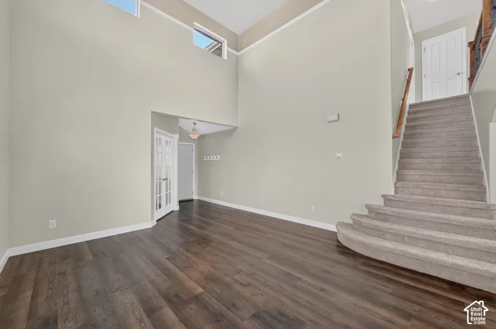 Vaulted ceiling with transom windows, wood-finish flooring, carpeted staircase, and French doors