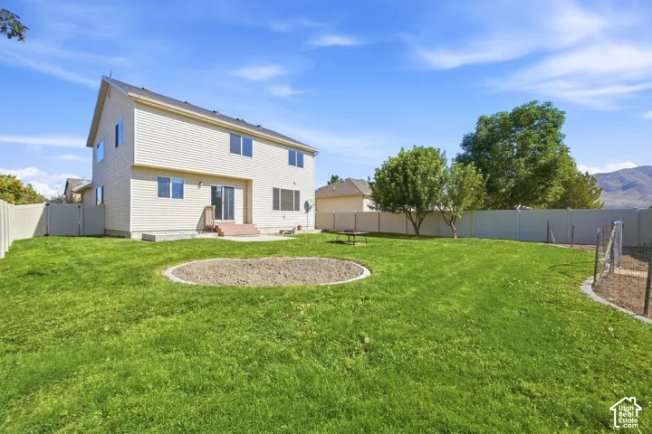 Expansive backyard with manicured lawn, mature landscaping, and circular stone patio