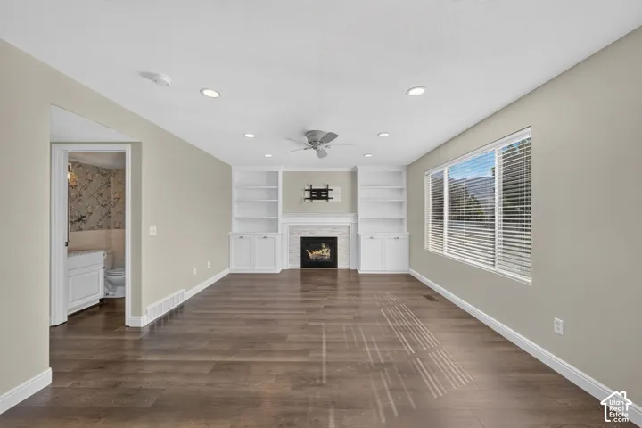 Spacious living room with wood-finish flooring, recessed ceiling lighting, and a ceiling fan