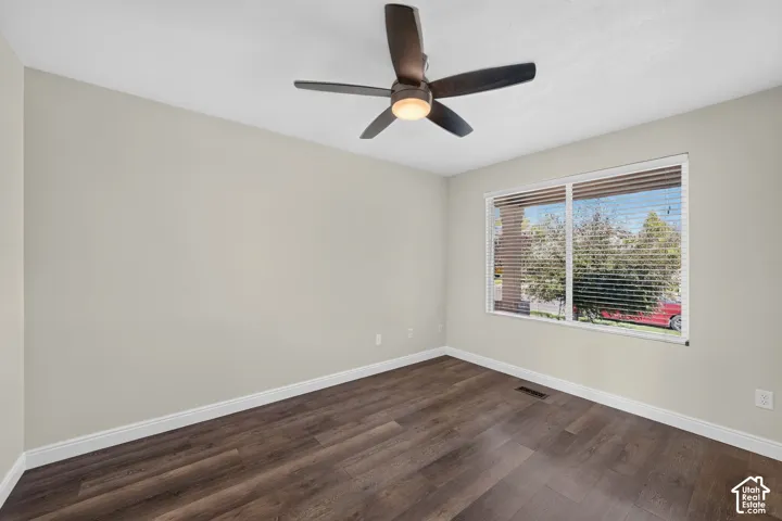 Neutral wall color, wood-finish flooring, white trim, window with blinds, and a ceiling fan with integrated lighting