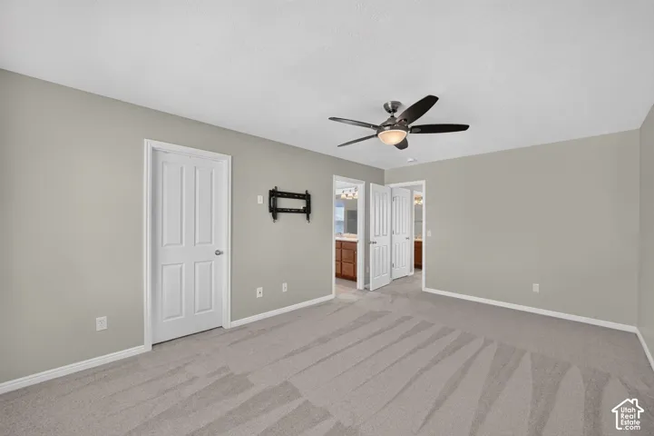 Light gray wall paint, textured ceiling, ceiling fan with integrated lighting, gray carpet flooring, white paneled doors
