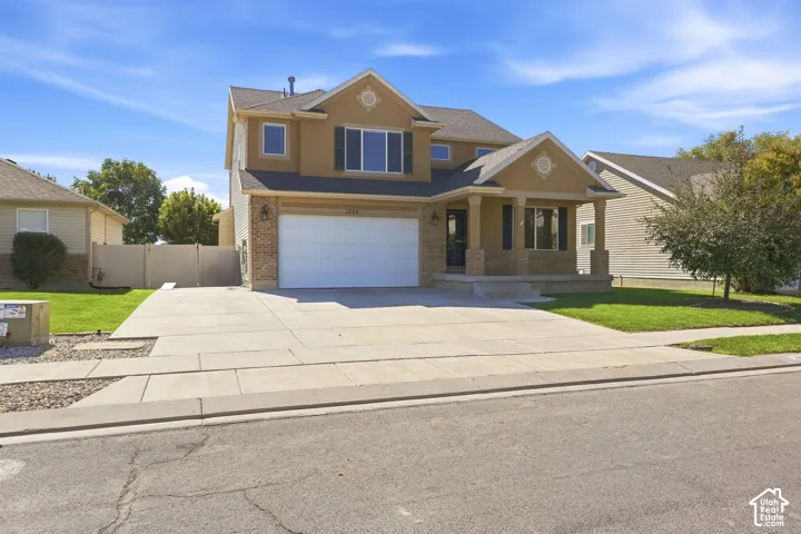 Two-story stucco exterior with stone accents, covered front porch, attached two-car garage, and concrete driveway