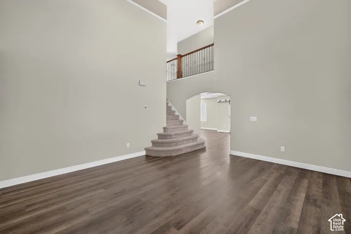 Soaring two-story foyer with curved staircase featuring wood-finish treads and metal railings