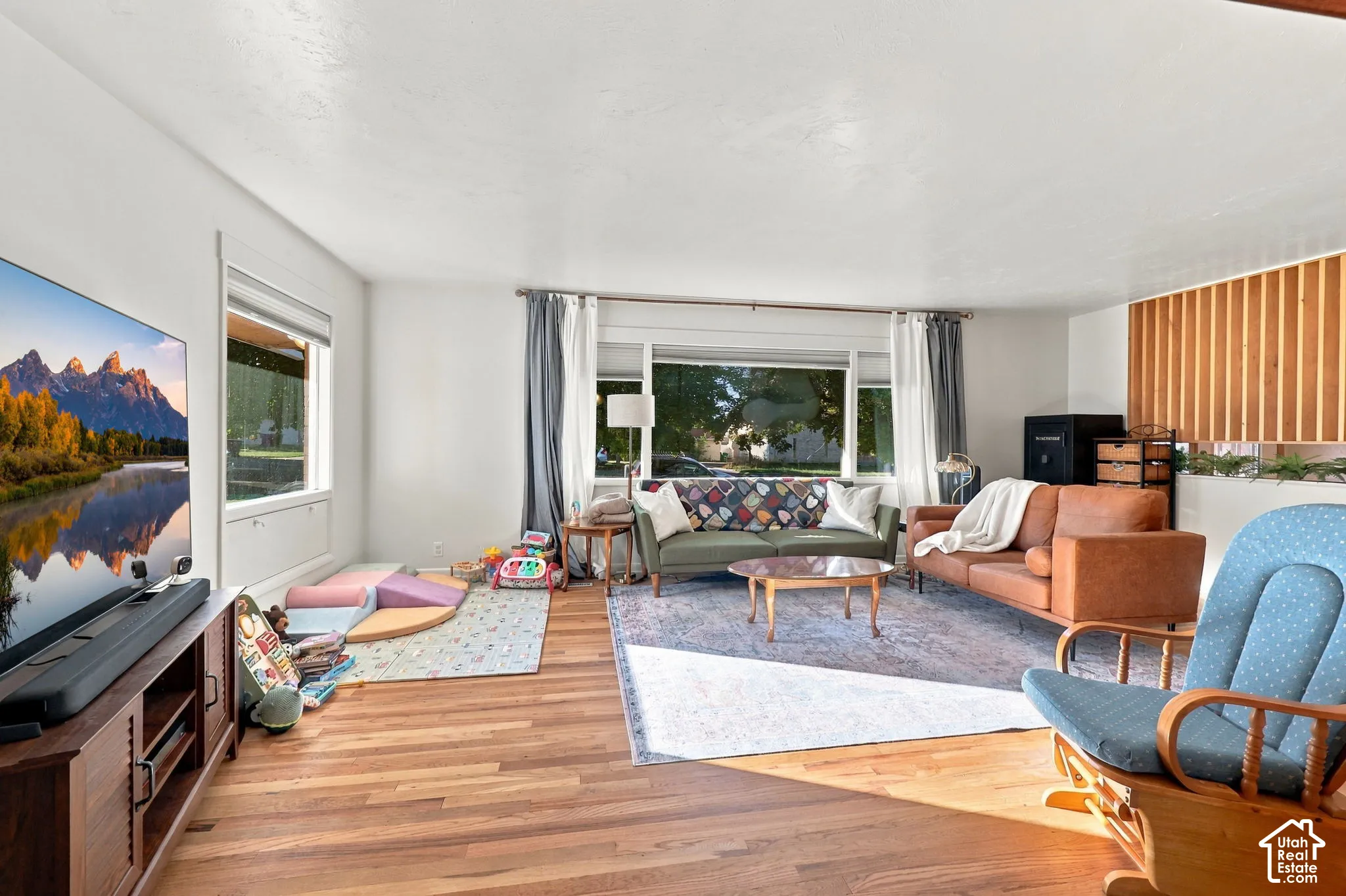 Hardwood flooring throughout, multiple windows, and a wood-slat accent wall
