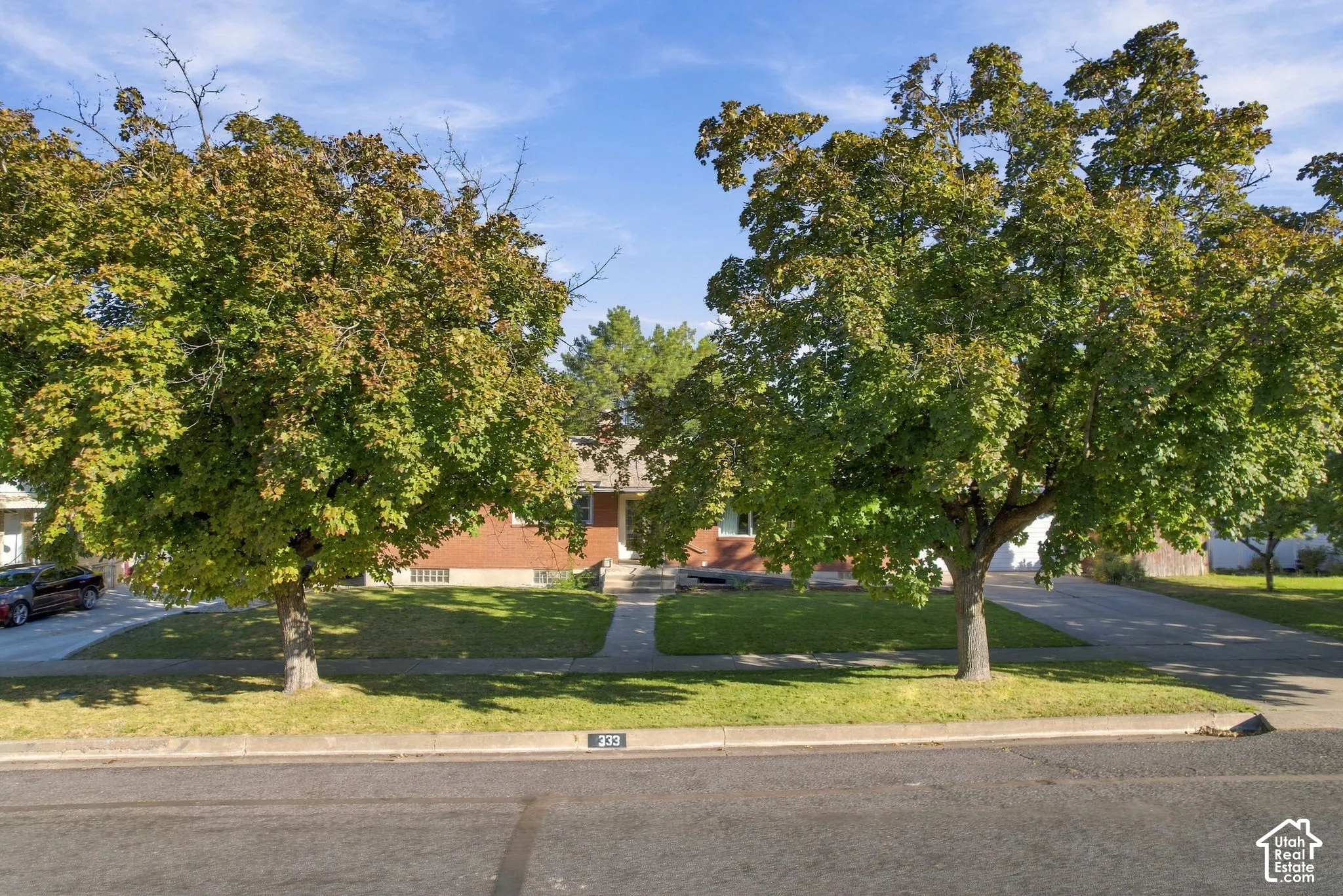 Brick exterior with a mature tree-lined front yard