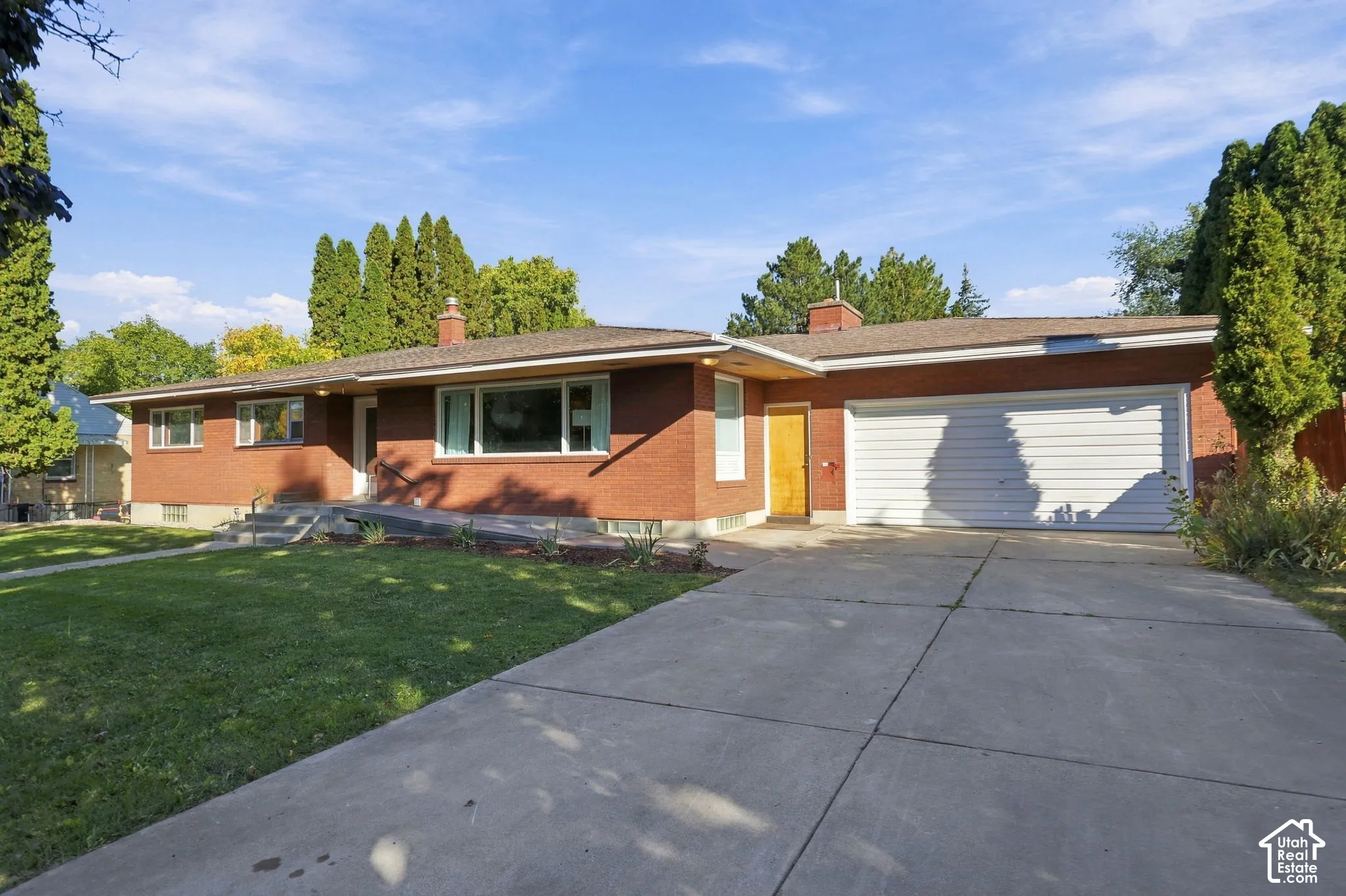 Brick exterior with a concrete driveway, attached garage, and front yard
