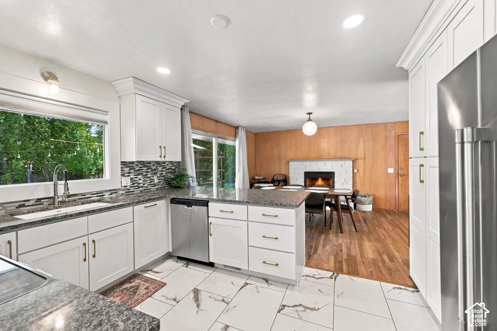 White cabinetry with gold-tone hardware, stainless steel appliances, granite countertops, and a tiled backsplash