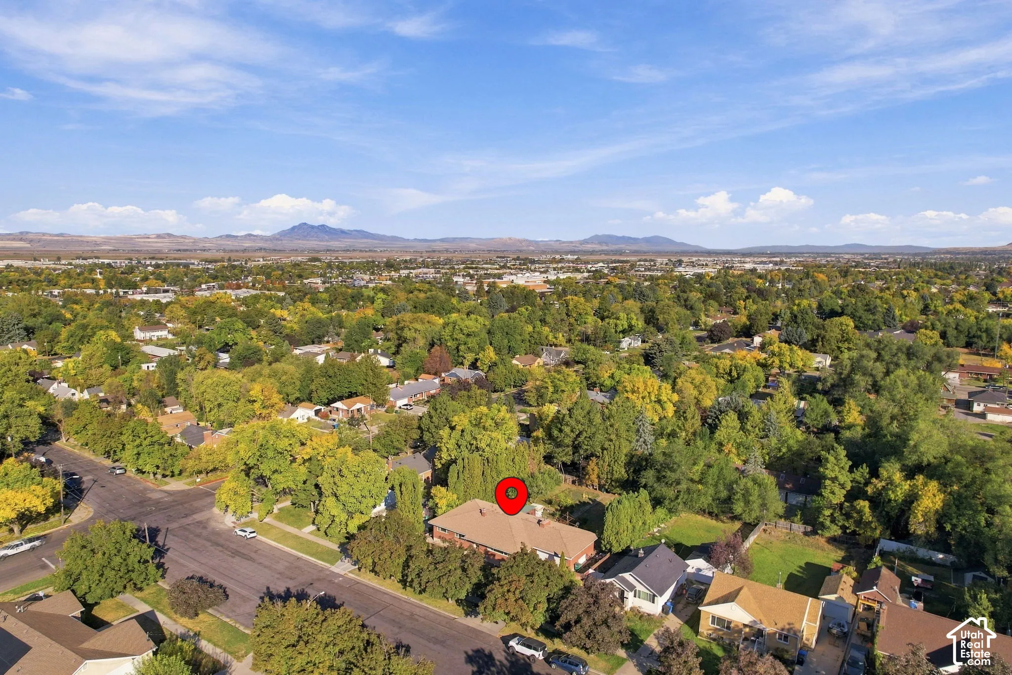 Expansive residential area with a prominent mountain backdrop, mature trees, and clear blue skies