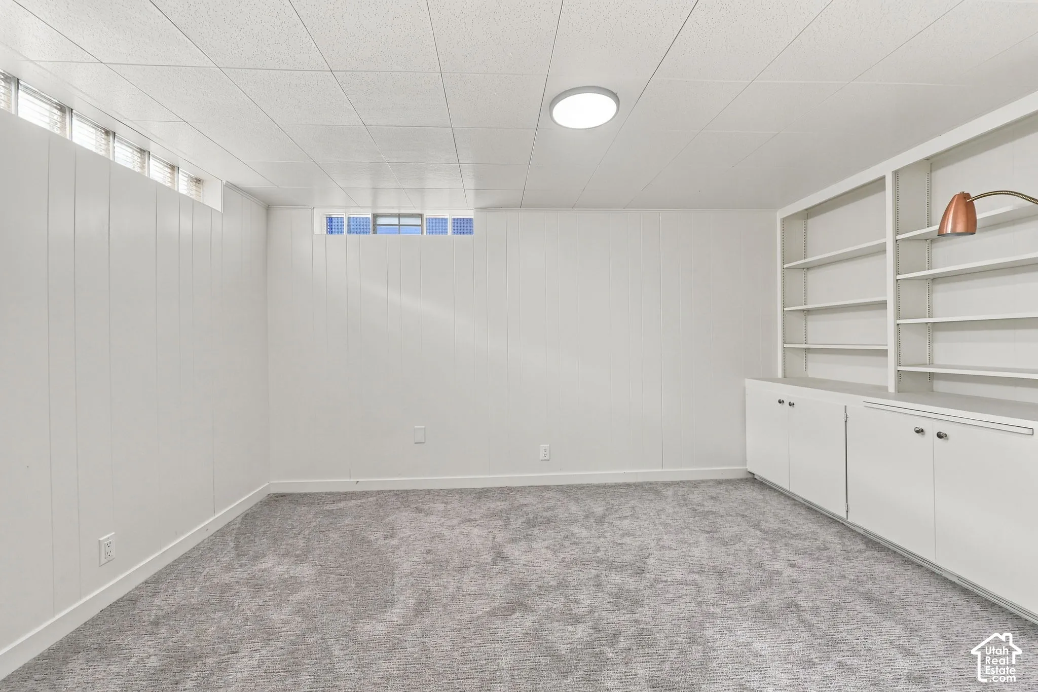 Versatile finished space featuring carpet flooring, recessed ceiling lighting, and custom built-in cabinetry with shelving and lower storage