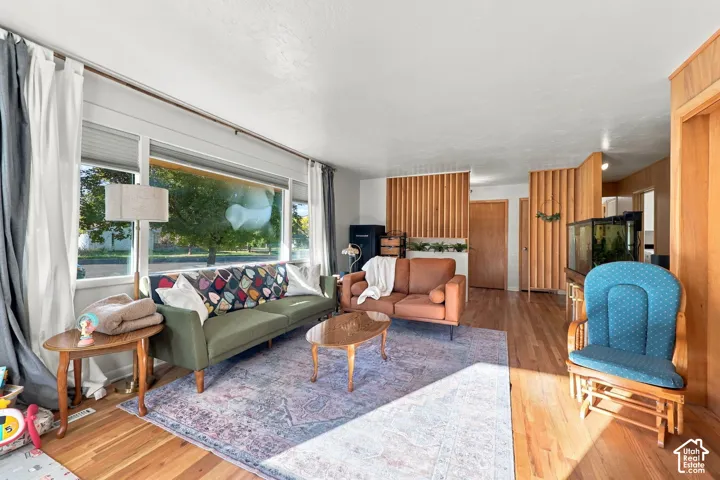 Hardwood flooring throughout, large picture window with roller shades, and natural wood paneling