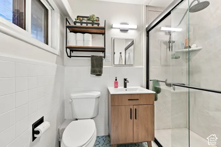 Contemporary bathroom featuring a walk-in shower with glass enclosure, wood-finish vanity with a vessel sink, square mirror, and wall-mounted light fixture