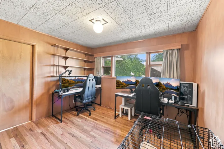 Dedicated home office featuring wood-finish flooring, natural light from multiple windows, built-in shelving, and a textured ceiling