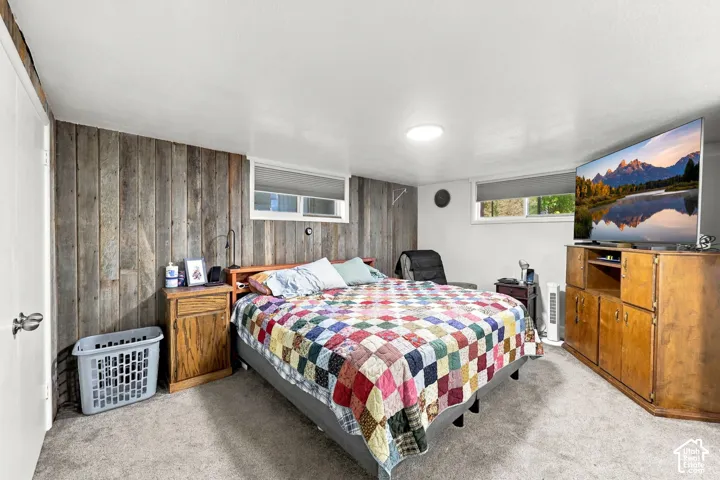 Carpeted flooring, wood-paneled accent wall, and recessed lighting with a window providing natural light