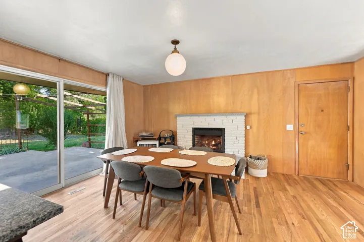 Hardwood flooring, wood paneling, white brick fireplace, sliding glass door, and a concrete patio