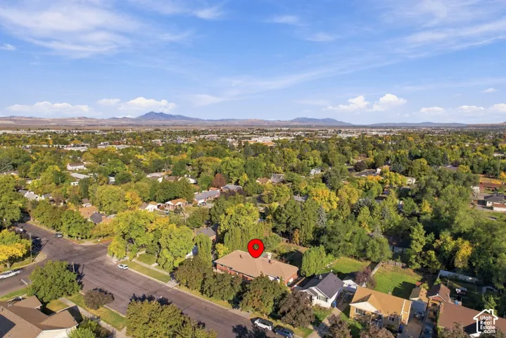 Expansive residential area with a prominent mountain backdrop, mature trees, and clear blue skies
