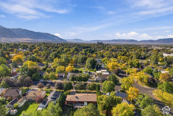 Expansive neighborhood featuring mature trees, residential properties, and distant mountain ranges under a clear sky