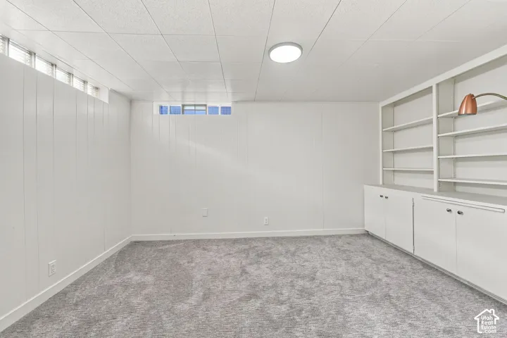 Versatile finished space featuring carpet flooring, recessed ceiling lighting, and custom built-in cabinetry with shelving and lower storage