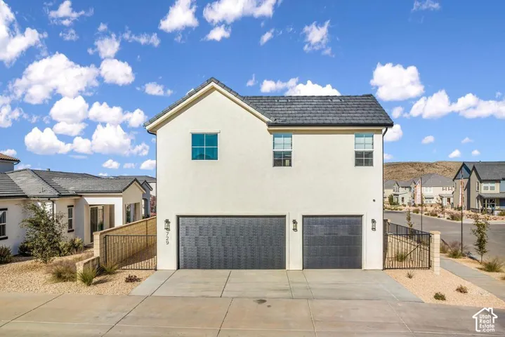 Stucco exterior featuring a dark tile roof, two garage bays with dark doors, and exterior wall sconces