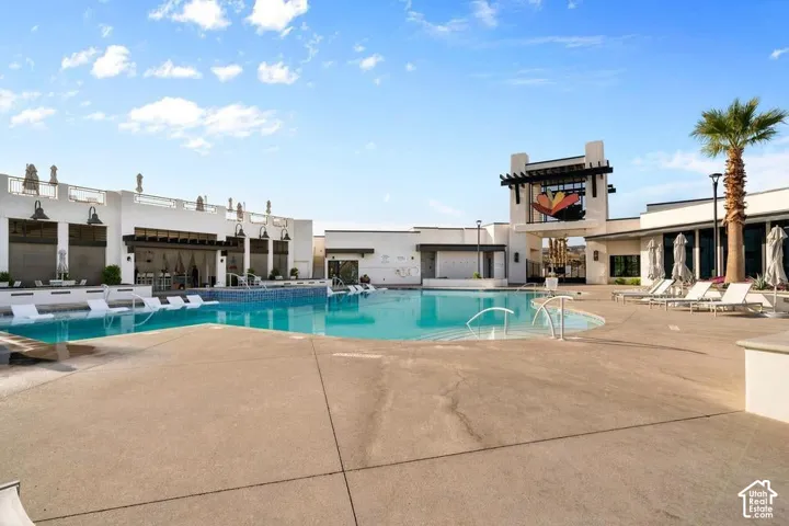 Resort-style pool area featuring crystal-clear turquoise water, expansive concrete decking, and modern architectural structures with clean lines
