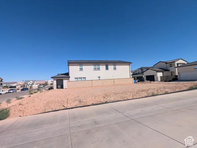 Cleared building lot with a sloped grade, featuring a paved road and curbside access
