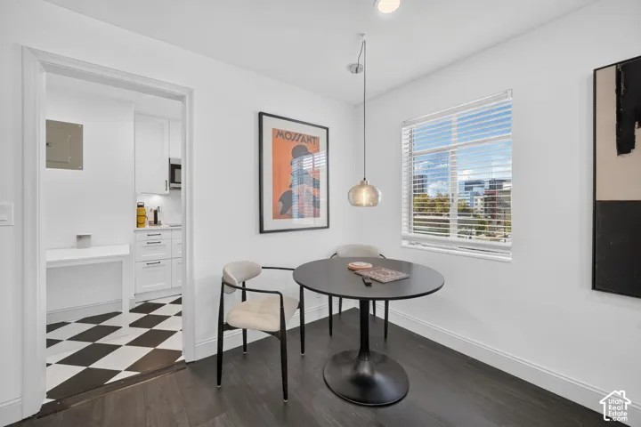 Modern dining area featuring a round pedestal table, contemporary pendant lighting, and abundant natural light from expansive windows with horizontal blinds