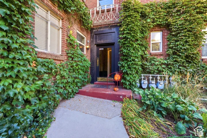Charming brick facade with lush ivy-covered exterior walls and ornamental ironwork detail above the entrance