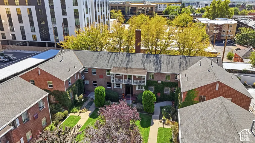 Brick exterior construction with multiple pitched roofs, featuring a central courtyard with manicured lawns and mature trees