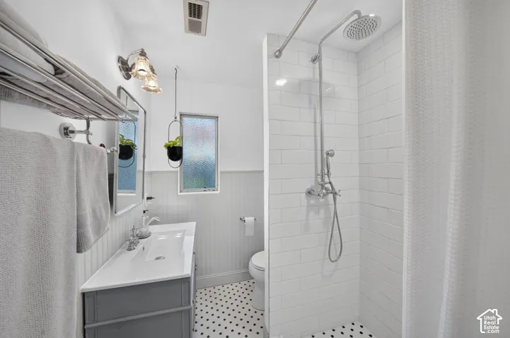 Modern bathroom featuring a floating vanity with rectangular vessel sink and integrated storage, white subway tile walls, polished concrete hex tile flooring, frameless glass shower enclosure with rainfall showerhead, and dual windows providing natural li