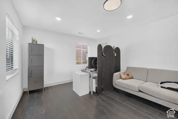 Modern home office featuring dark wood-finish flooring, recessed ceiling lighting, and built-in storage cabinetry