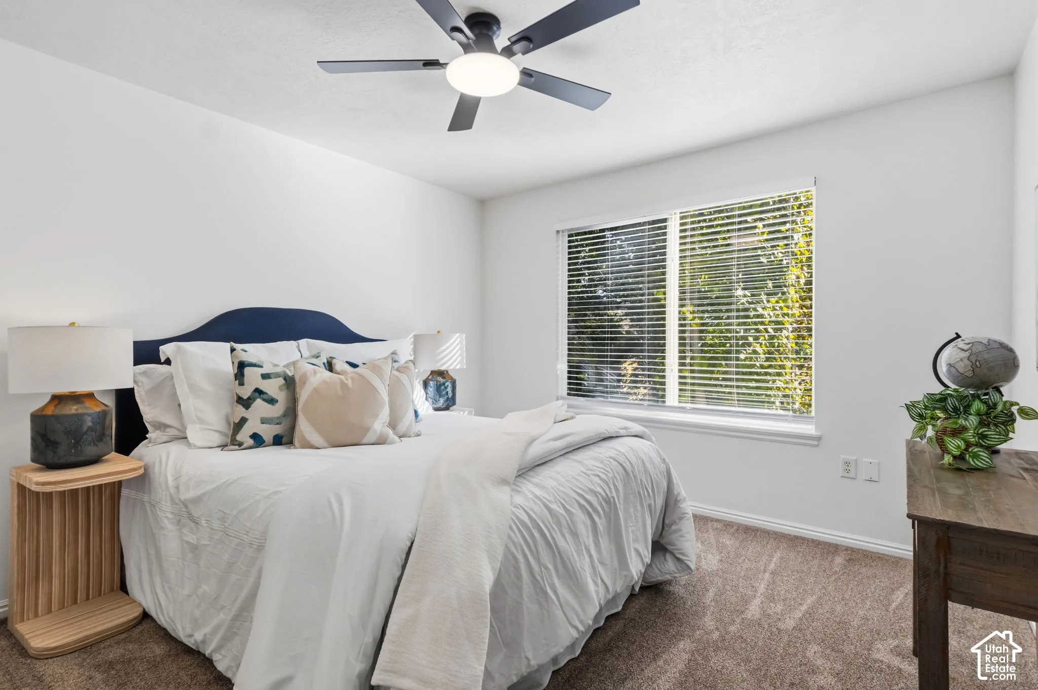 Spacious room featuring a ceiling fan with integrated lighting, a large window with blinds, and neutral carpet flooring