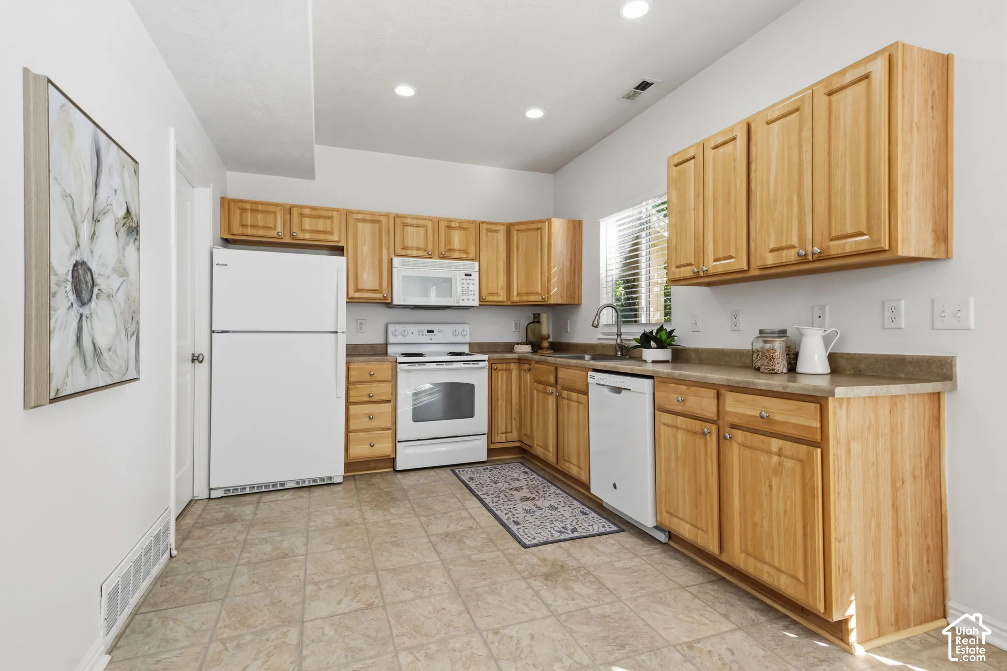 Kitchen featuring wood cabinetry, white appliances, light-toned countertops, and recessed lighting