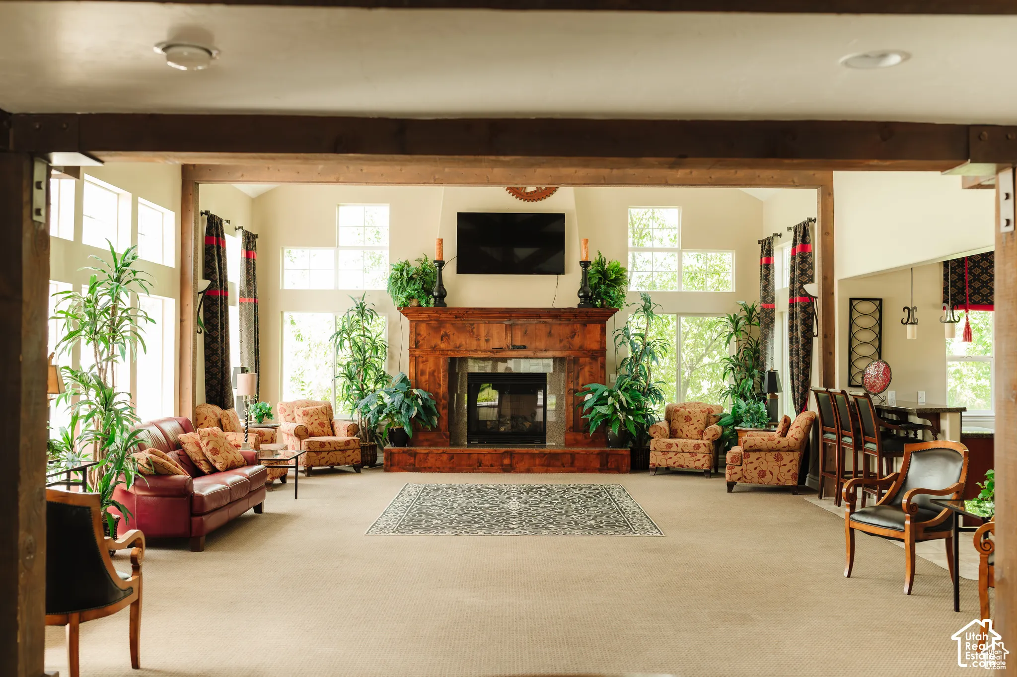 Vaulted ceilings featuring exposed structural timber beams, floor-to-ceiling windows, and a prominent wood-clad fireplace surround