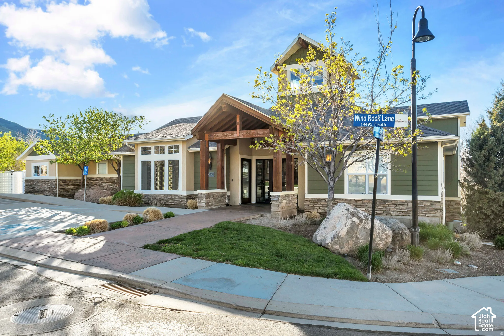 Exterior facade featuring timber-framed entry, stacked stone accents, horizontal siding, and a central cupola