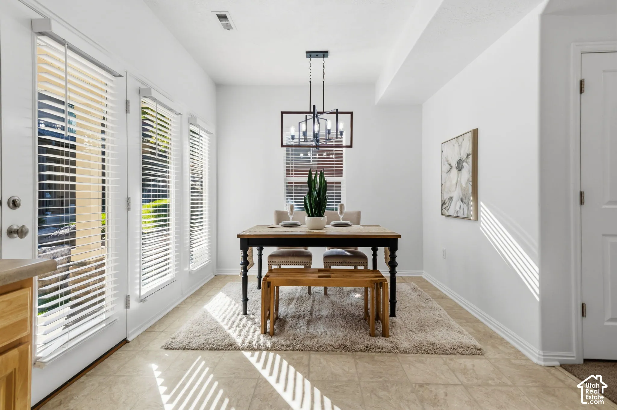 Recessed ceiling, neutral wall paint, tile flooring, modern chandelier, and multiple windows with blinds