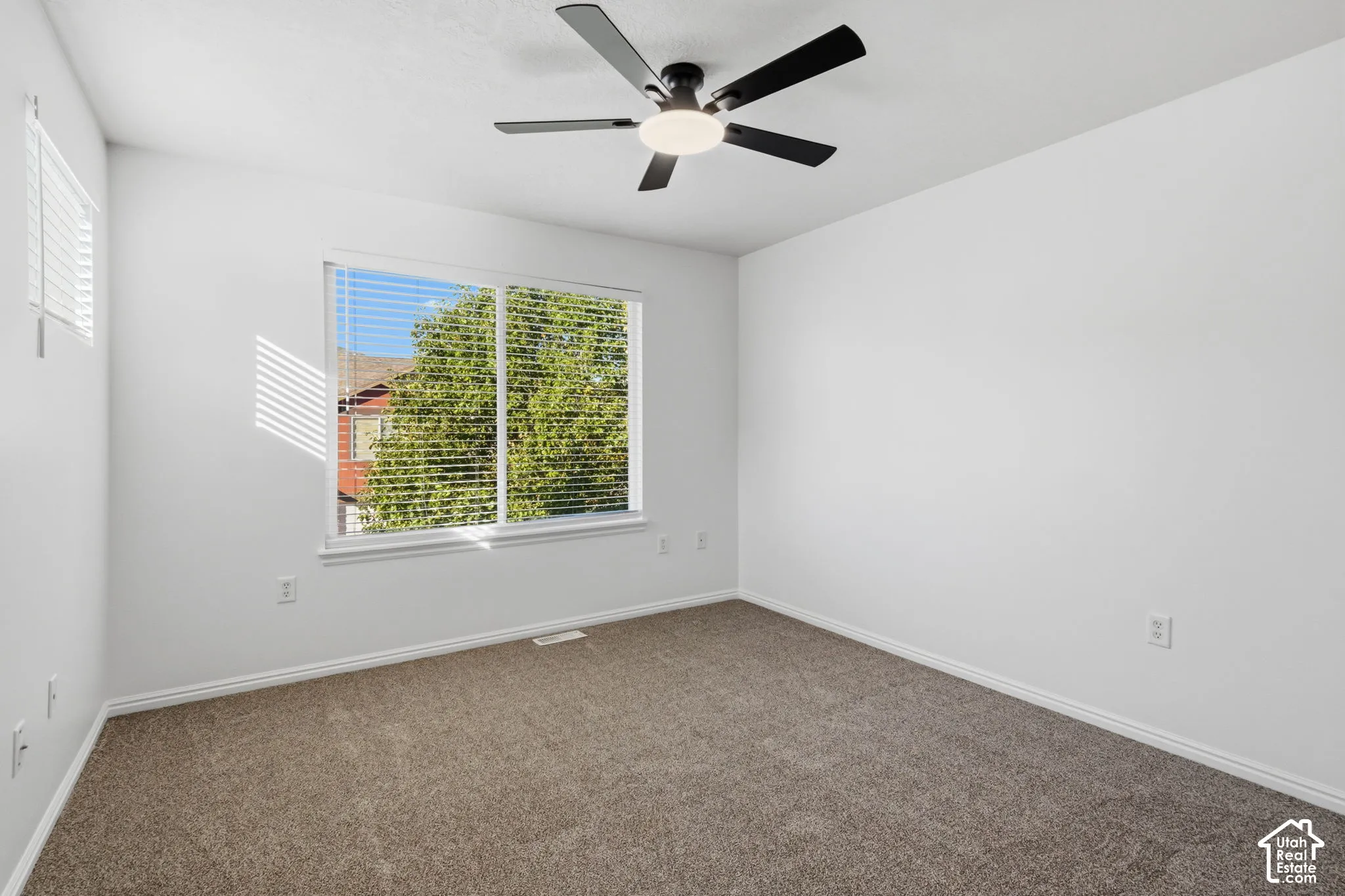 Recessed window with white blinds, neutral carpeting, and a ceiling fan with integrated lighting